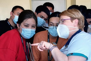 People in masks watching one woman, who's pointing at something